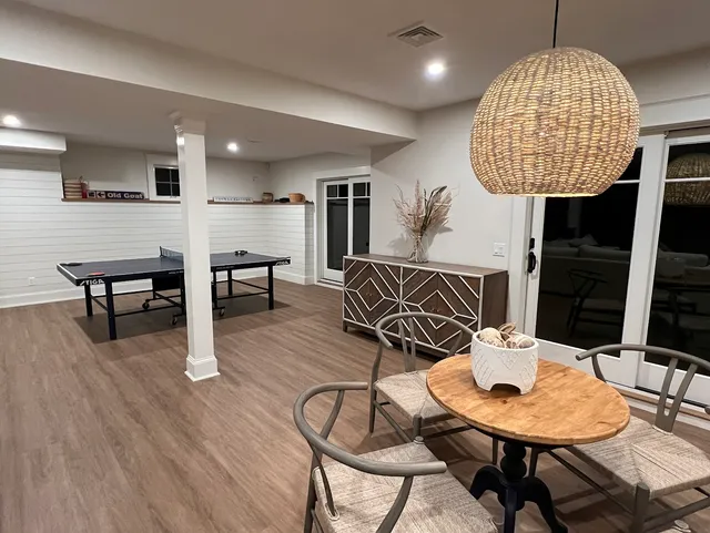 Finished lower-level game room with shiplap and wide-plank flooring