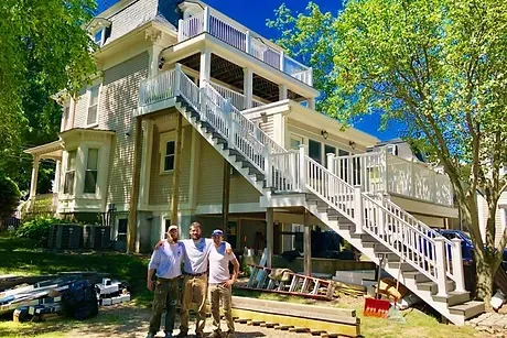 3 Team members from Rand's Carpentry Service standing in front of a colonial style house.