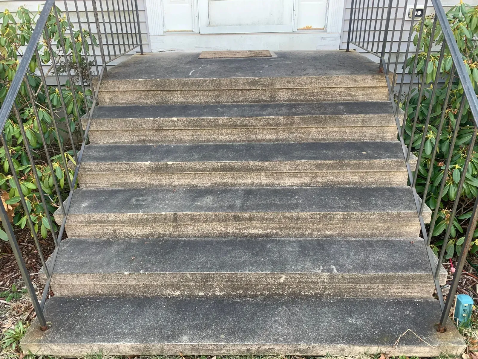 A set of stairs leading up to a house with a metal railing.