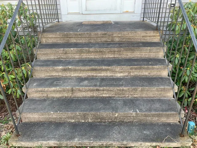 A set of stairs leading up to a house with a metal railing.