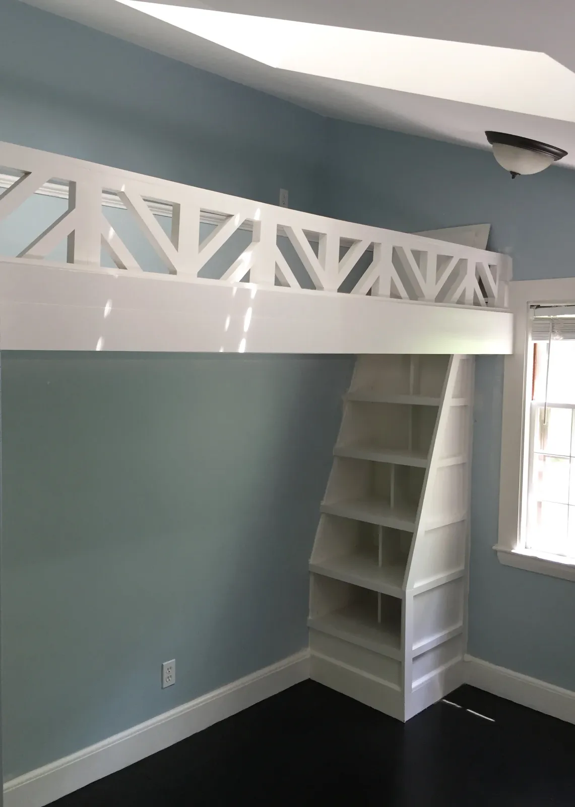 A whimsical playspace loft with trap door and bookcase "ladder" created for a girl's bedroom.