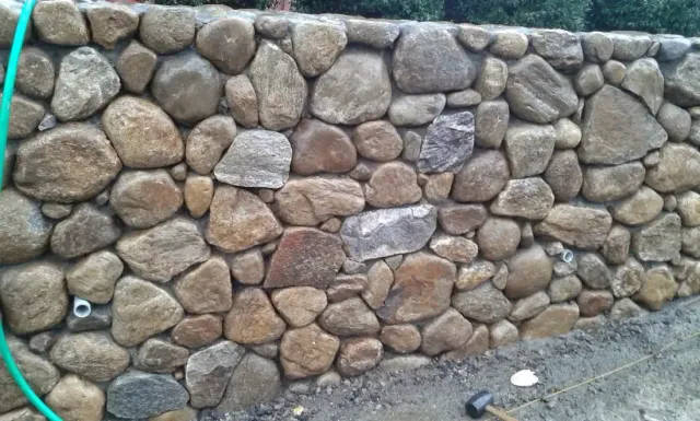 Close detail of a mortared round fieldstone wall in progress