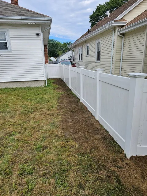 a white fence surrounds the backyard of a house