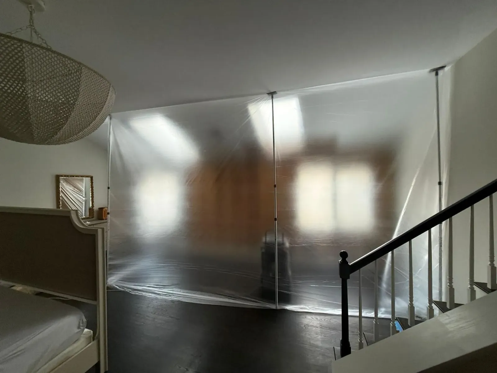 Bedroom with a bed, frosted wall panels, and a staircase railing in the foreground.