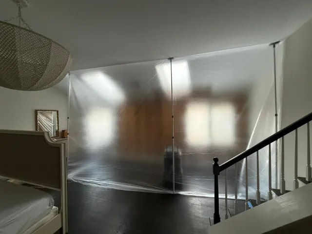 Bedroom with a bed, frosted wall panels, and a staircase railing in the foreground.