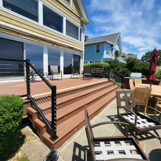 sunny-backyard-deck-with-stairs-patio-furniture-and-coastal-houses.webp