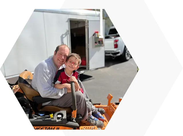 A man and boy sitting on top of a truck.