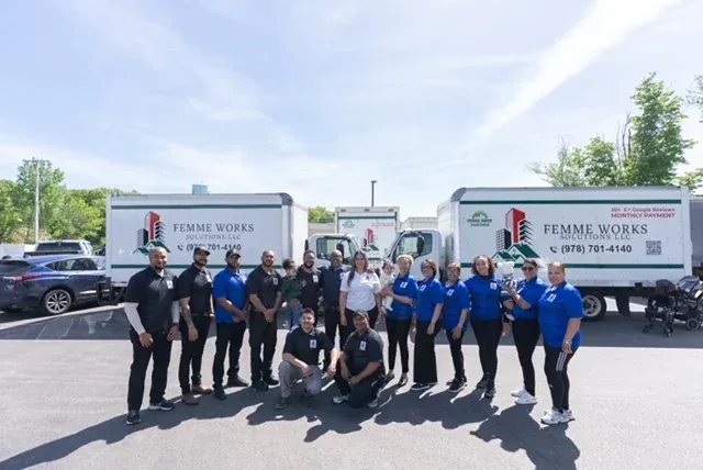 Femme Works Solutions team standing with company service trucks