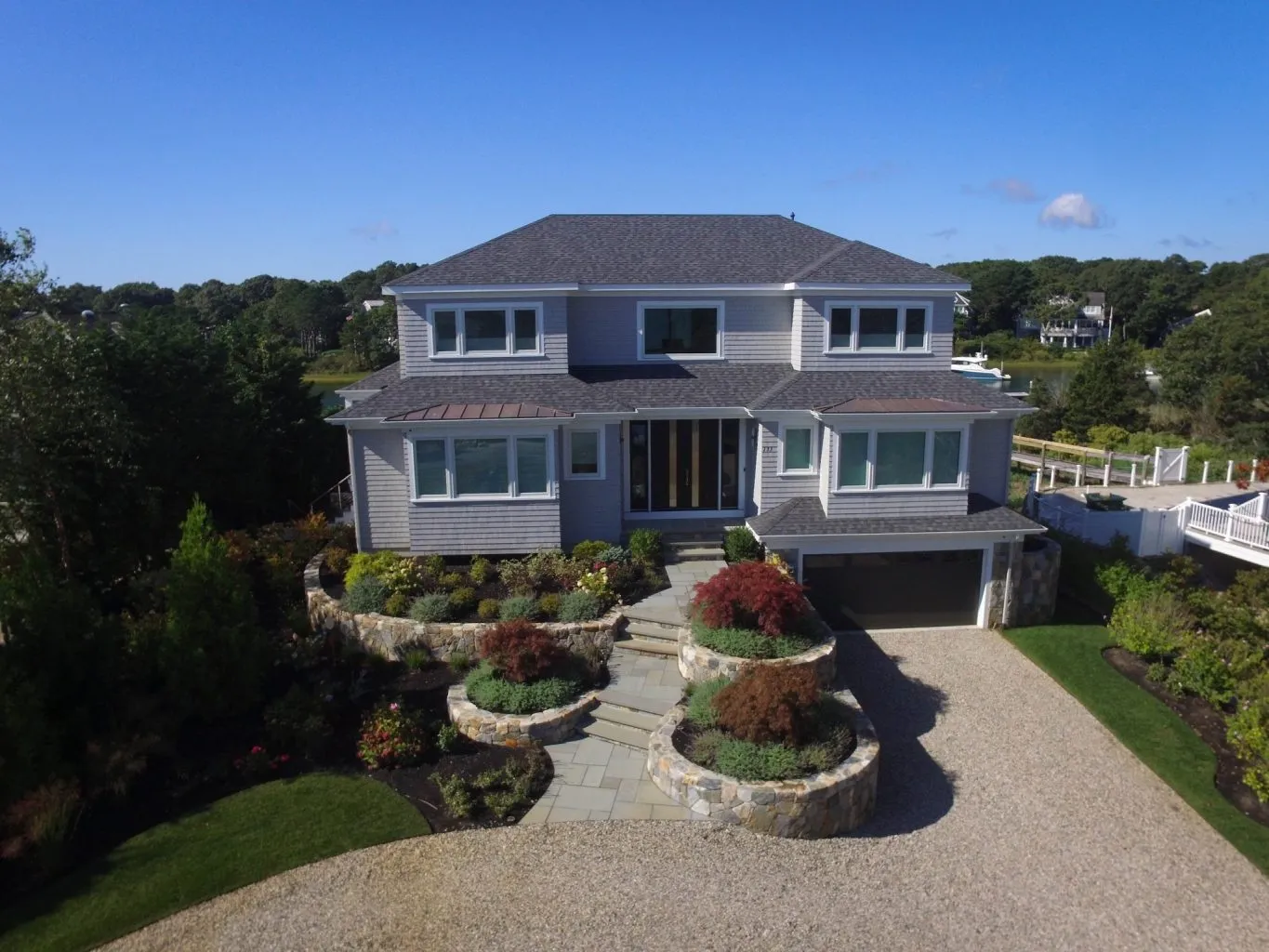 Large home with stone driveway, lower level garage, teired stairway