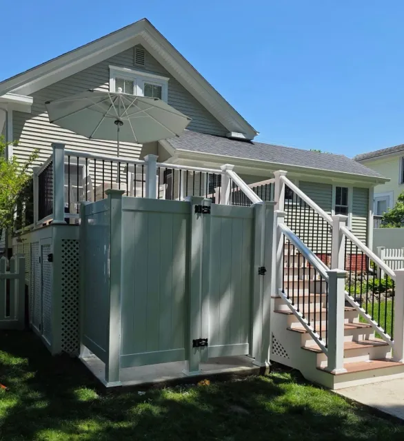 Backyard patio with white stairs, large umbrella, and a gray storage shed beside a house