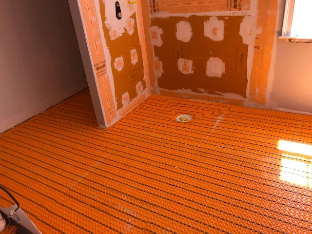 Unfinished room with orange flooring, patchy walls, and sunlight on the floor.