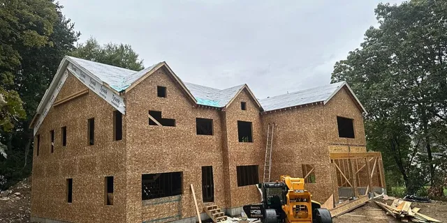 Large-scale custom home framing and roof underlayment installation project with JCB equipment in Sudbury MA