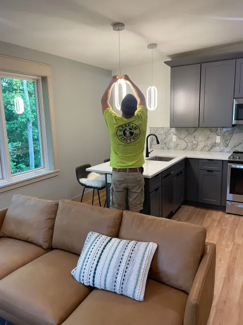 A man is installing a light fixture in a living room.