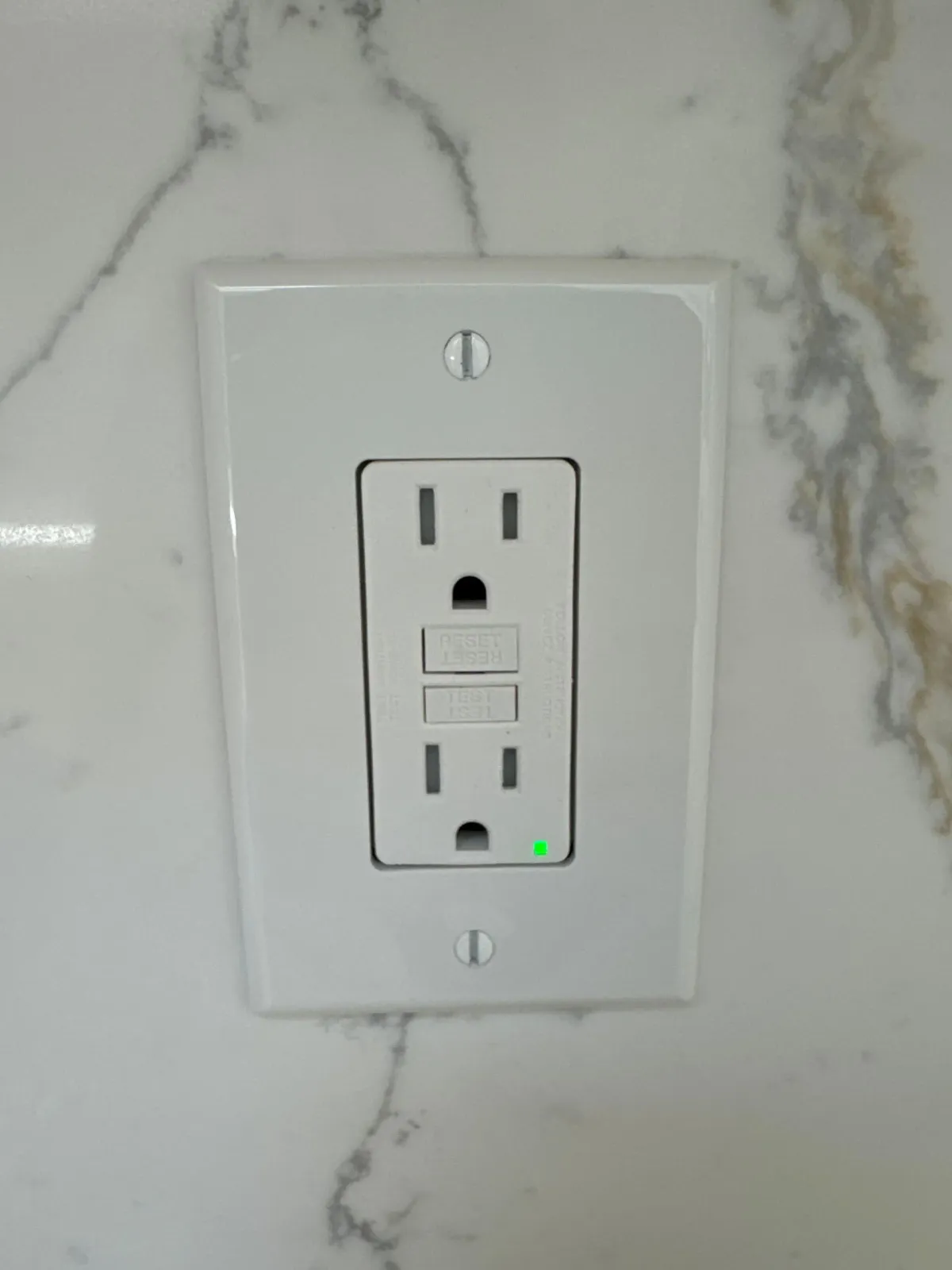 Electrical outlets and switch with exposed wiring set in a gray wall.
