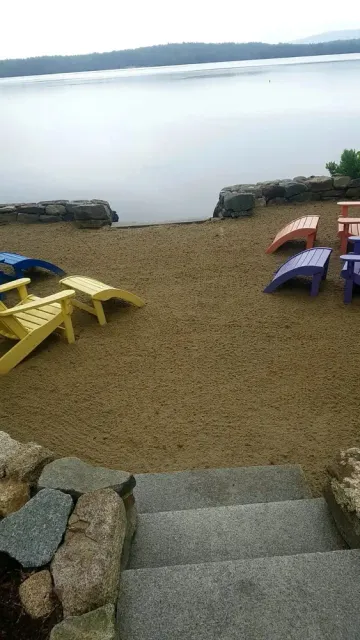 Colorful Adirondack chairs waiting on a sandy lakeside beach