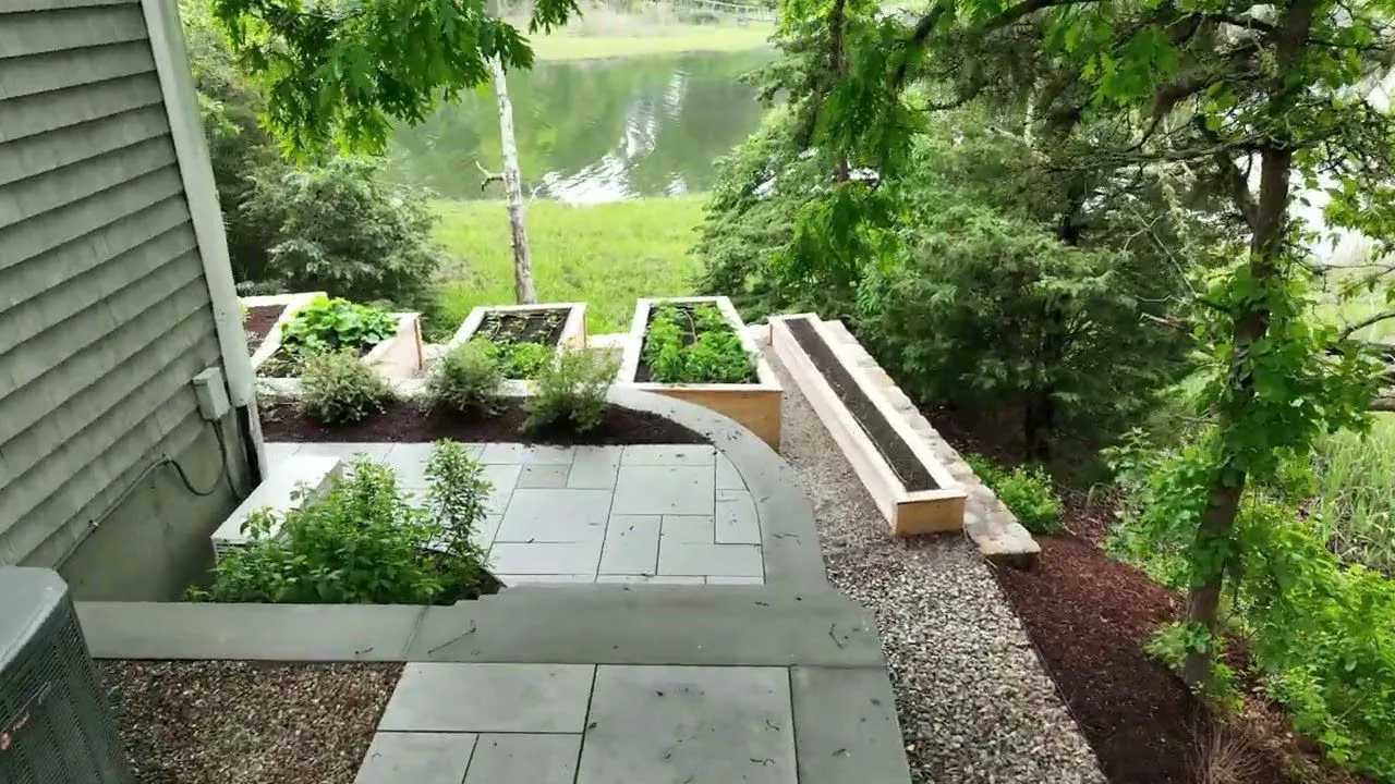 A bluestone walkway and raised garden beds overlooking a Cape Cod harbor — featured project by Blue Claw Associates