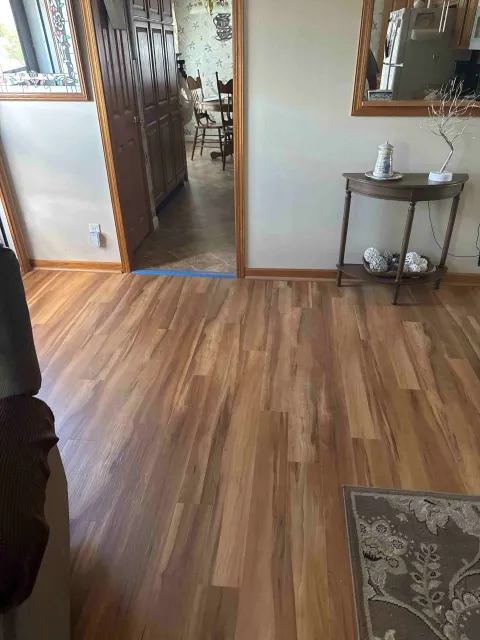 Wooden floors in a living room with an entryway to a dining room and a table with decor.