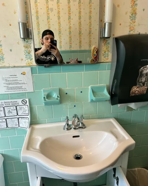 A man is taking a picture of himself in a bathroom sink.