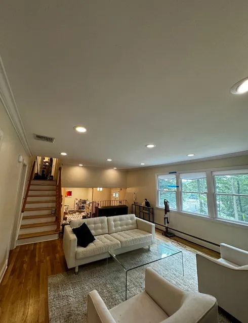 Living Room with Recessed Lighting, White Furniture, and a Staircase Leading Upstairs