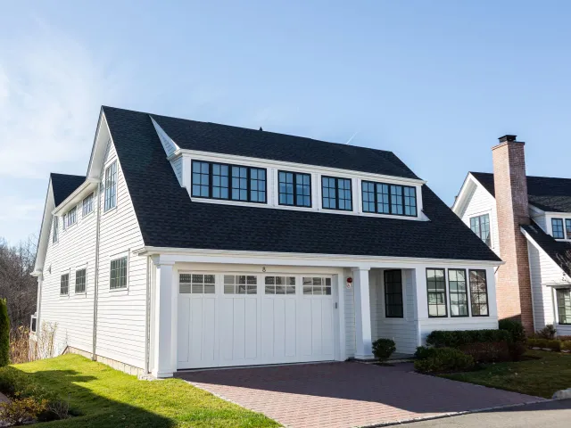 A white house with a black roof and solar panels on the roof