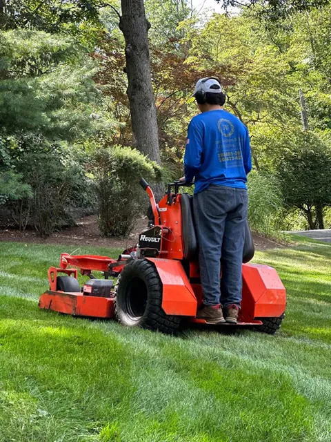 A man is riding a lawn mower on a lush green lawn