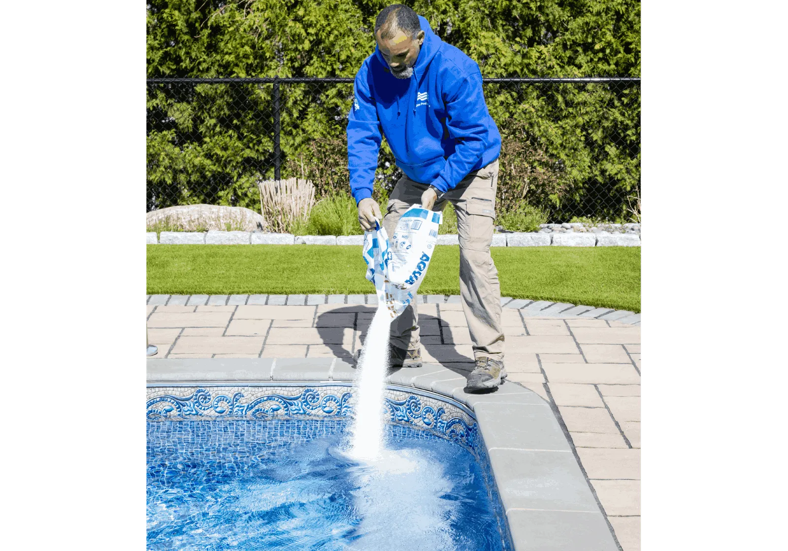 A man in blue jacket pouring water into pool.
