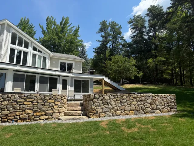 Lakeside home with a screened porch, stone steps, and finished landscaping