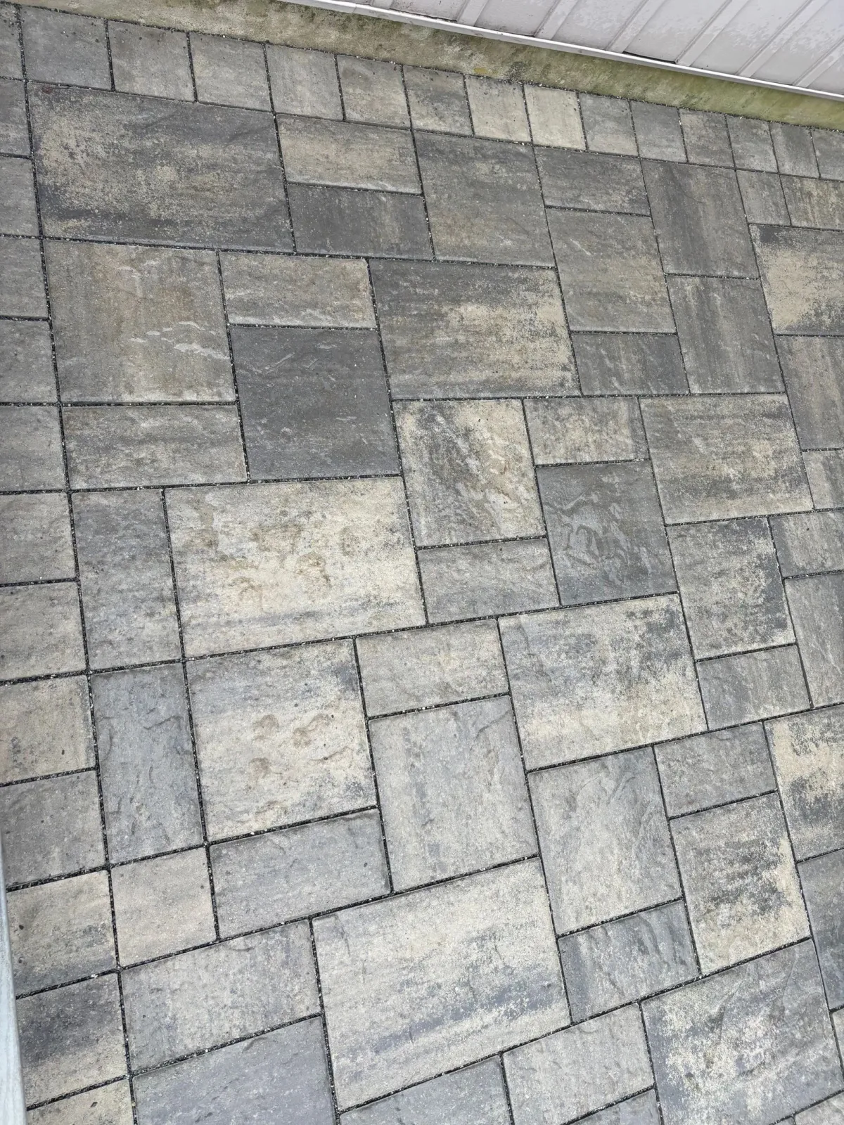 Gray and tan rectangular pavers arranged in a random pattern on a patio.