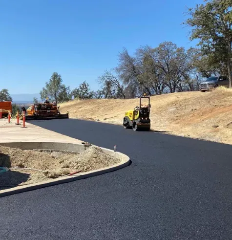 Road paving crew working on a newly paved asphalt road on a sunny hillside