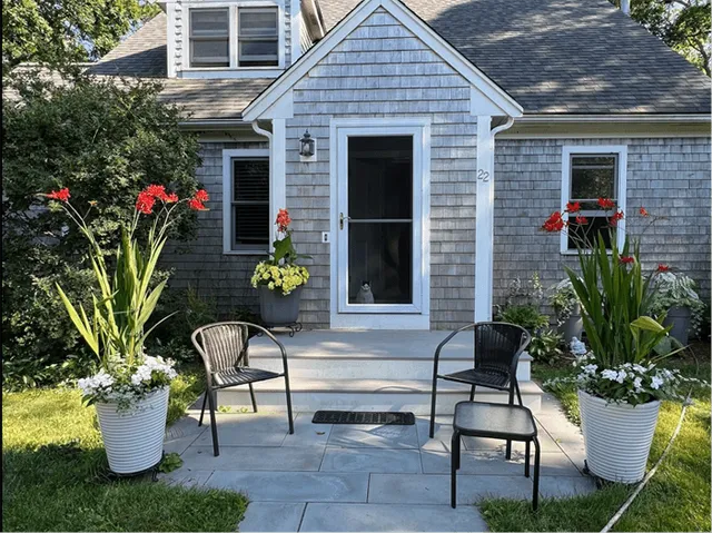 A house with two chairs and potted plants.