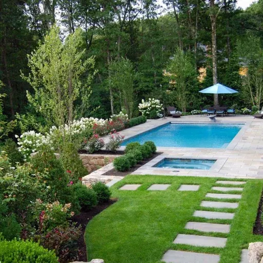 A Needham rectangular pool with bluestone paving, an integrated spa, and woodland garden planting creates a serene backyard destination.