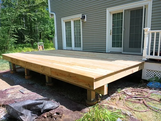 Early framing stage for a Bedford deck rebuild beside a future porch addition