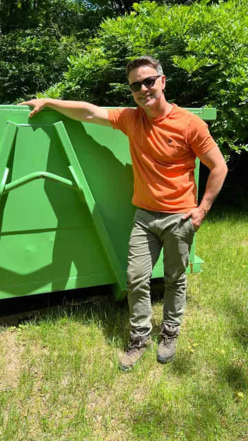 Owner standing next to green dumpster