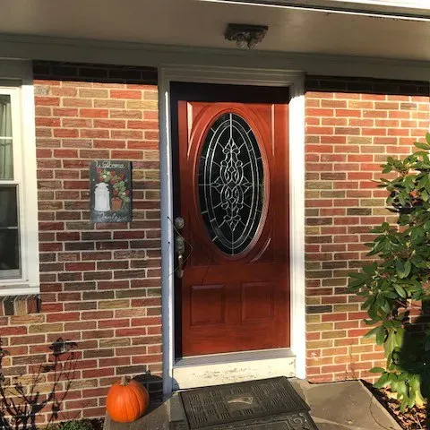 A brick house with a wooden door and a pumpkin on the porch