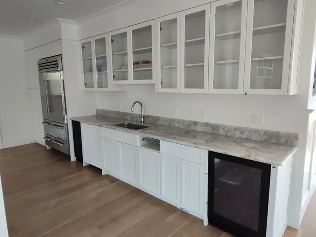 Remodeled kitchen with white cabinetry, stone countertops and a beverage fridge