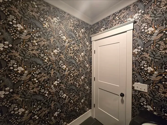 Powder room with dark floral wallpaper and crisp white trim