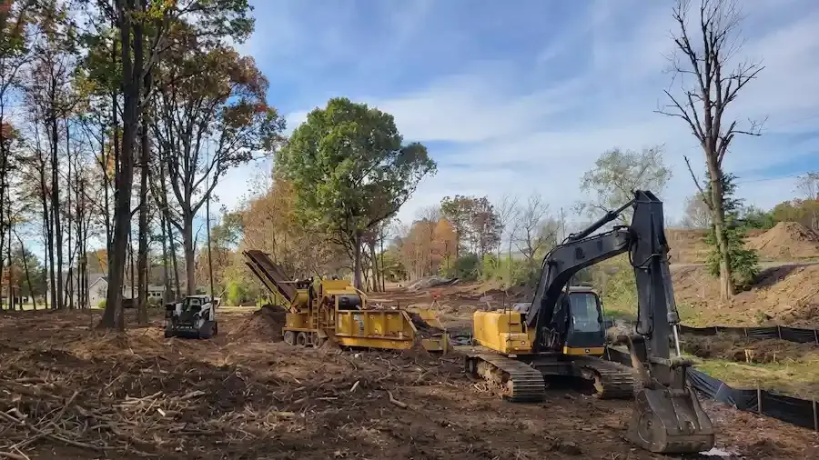 Yellow excavator working on land clearing and grading project