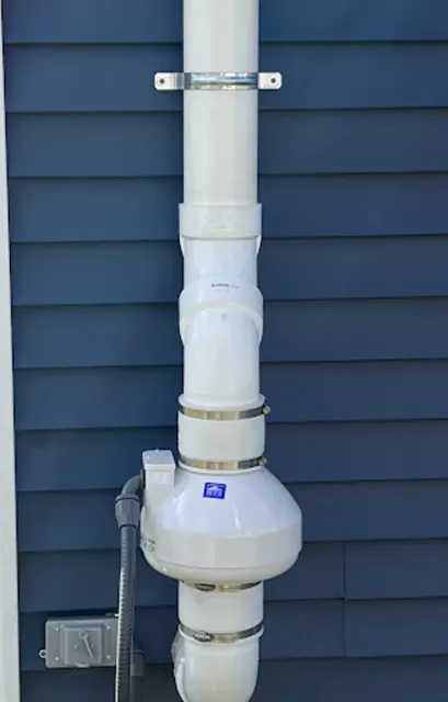 A white pipe is attached to the side of a blue house