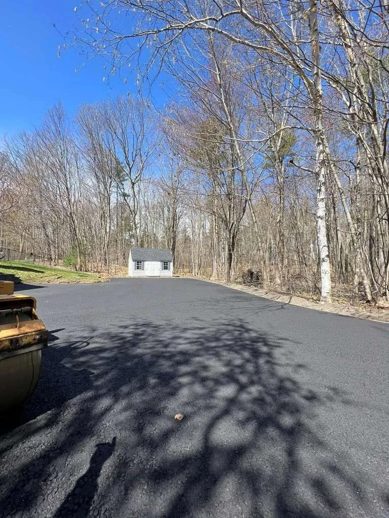 New asphalt driveway with a small house in background