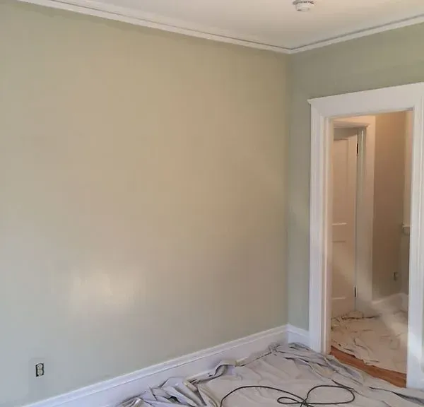 Empty beige room with white trim and doorway, cables on the floor, under renovation