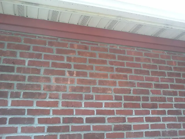 Brick wall with a red wooden trim under a white ceiling.