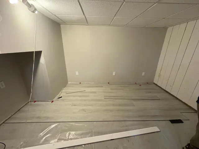 Light luxury vinyl plank flooring being installed across the basement remodel
