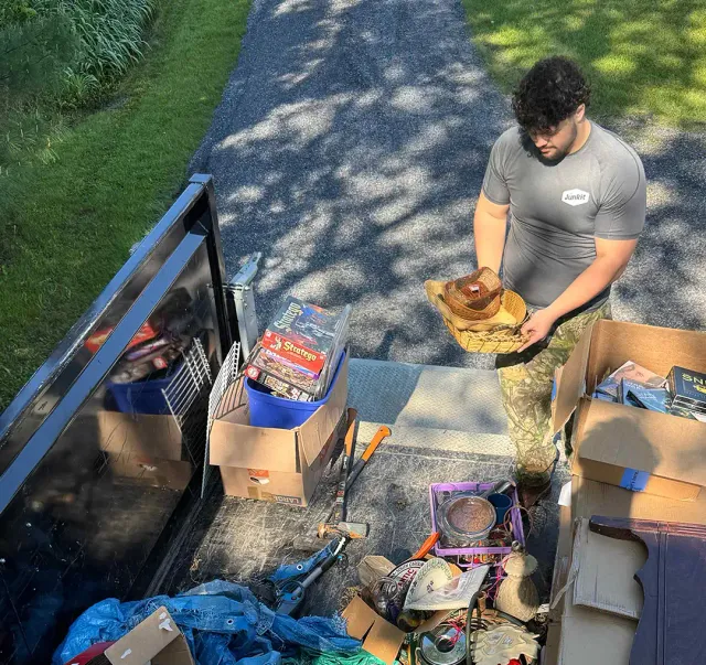 Team member organizing items for donation and disposal in truck bed