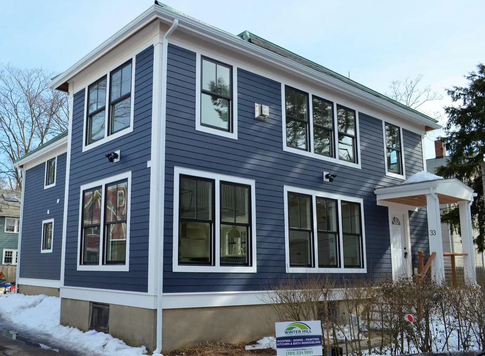 Completed navy siding, trim and window replacement with Winter Hill General Contractor job sign