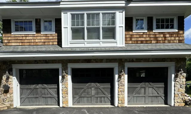 Modern outdoor living space with taupe exterior siding painted by CYR Painting Services featuring cedar timber frame porch roof, black window trim, and stone pillars on stone patio - metal exterior