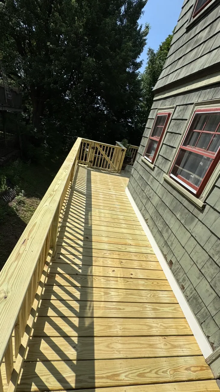 Long pressure-treated elevated walkway along a shingled house