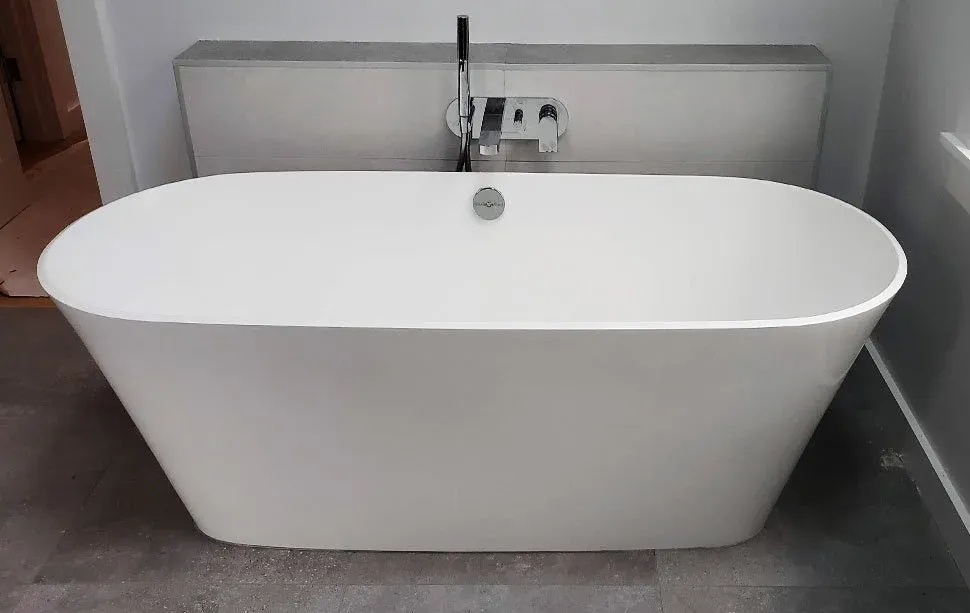 A modern, freestanding white bathtub with a curved shape in a bathroom.