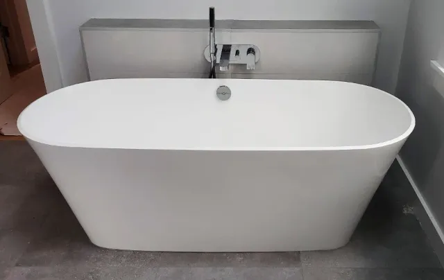 A modern, freestanding white bathtub with a curved shape in a bathroom.