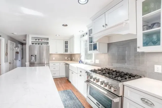 Bright white modern kitchen with stainless steel appliances, large island, and tiled backsplash