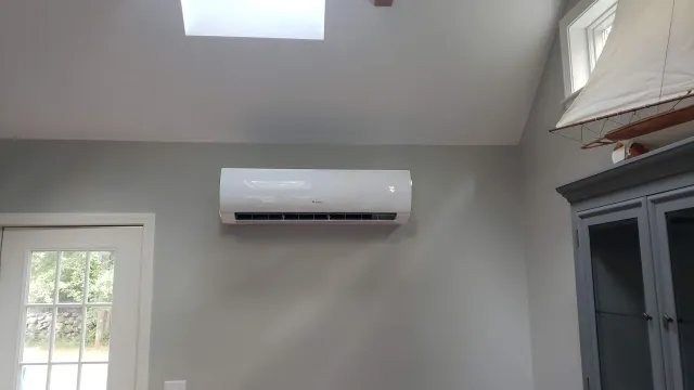 A room with a window and a fan on the wall.